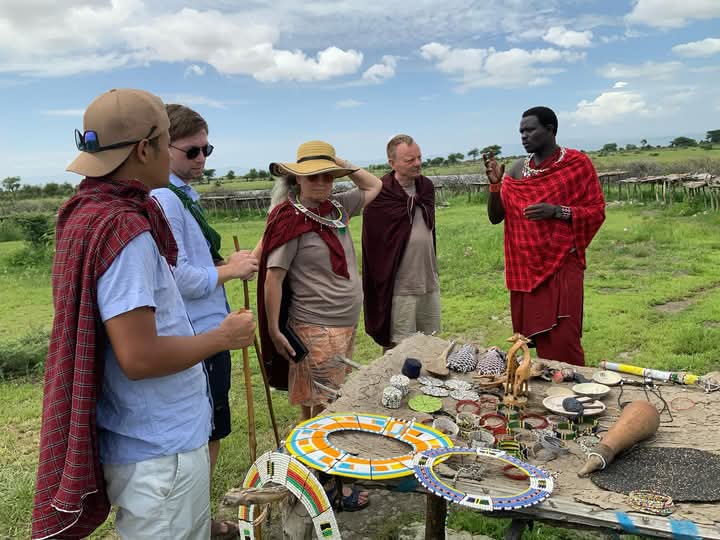 Maasai guide showing traditional crafts to tourists